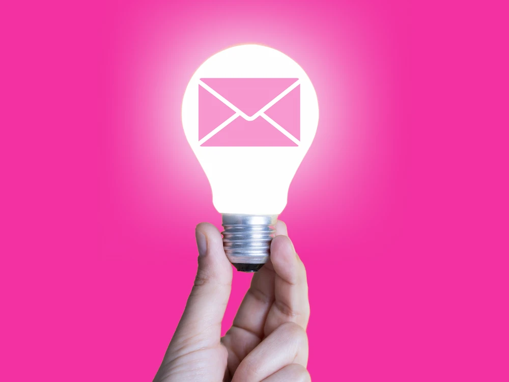 A man holding a glowing lightbulb with mail icon on it
