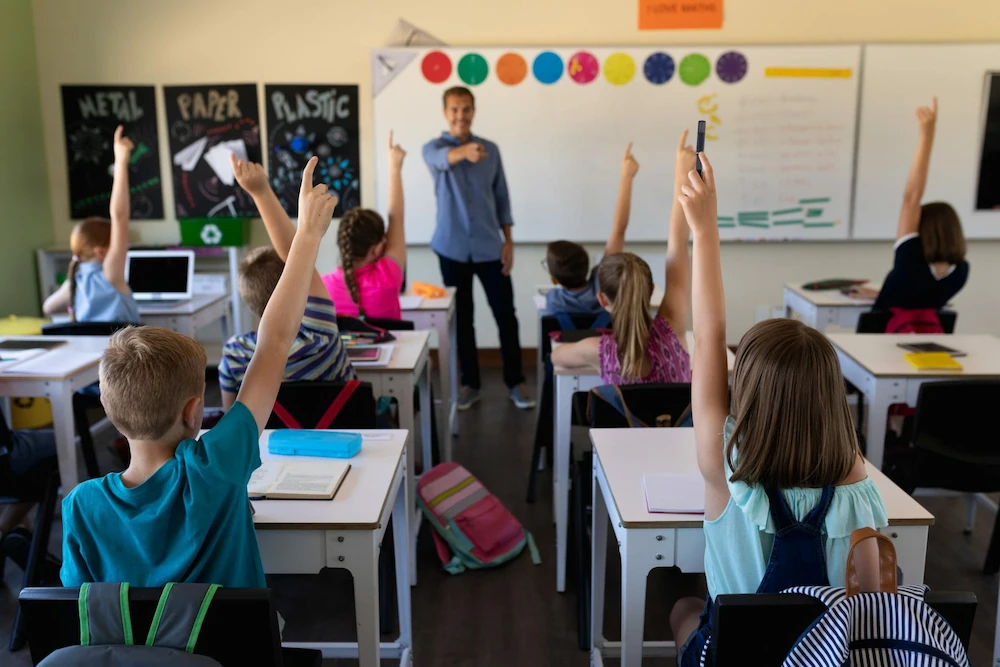 A school teacher standing in front of a classroom with kids